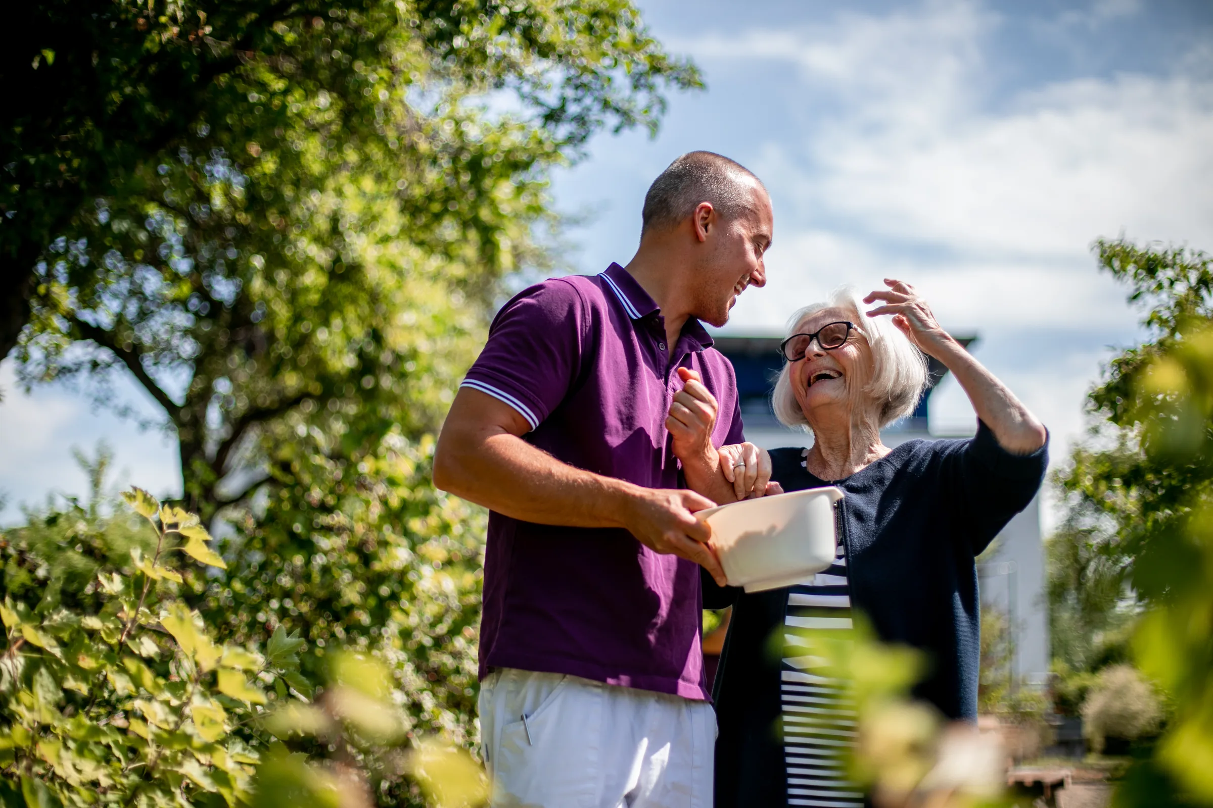 Seniorin und Alltagsbegleiter bei der Gartenarbeit